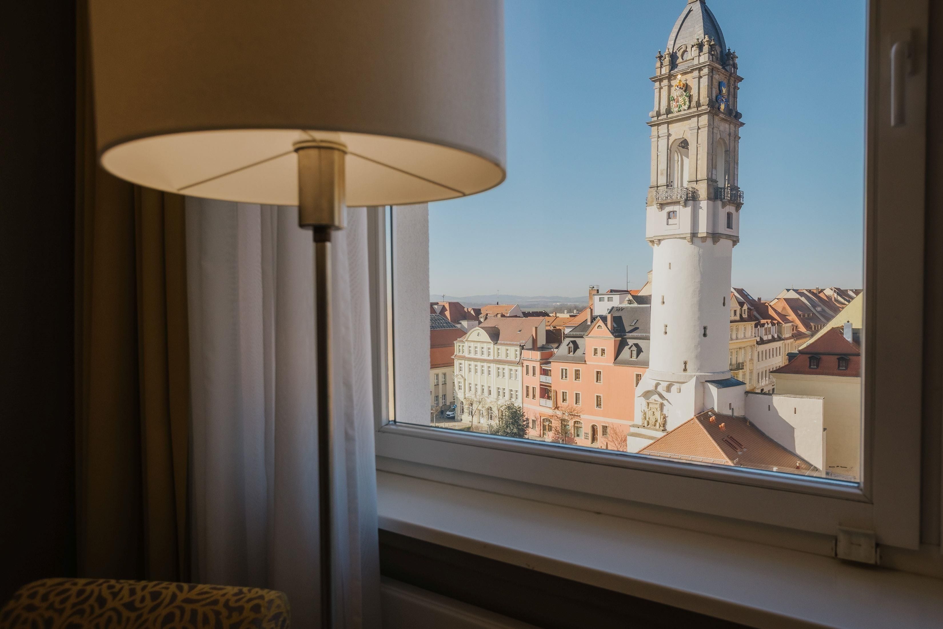 Una habitación con vista a una torre y edificios a través de una ventana.