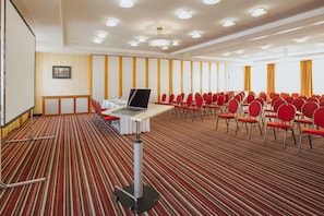 A conference room with a carpeted floor, a table with a laptop, and rows of red chairs. - Best Western Plus Hotel Bautzen (Bautzen)