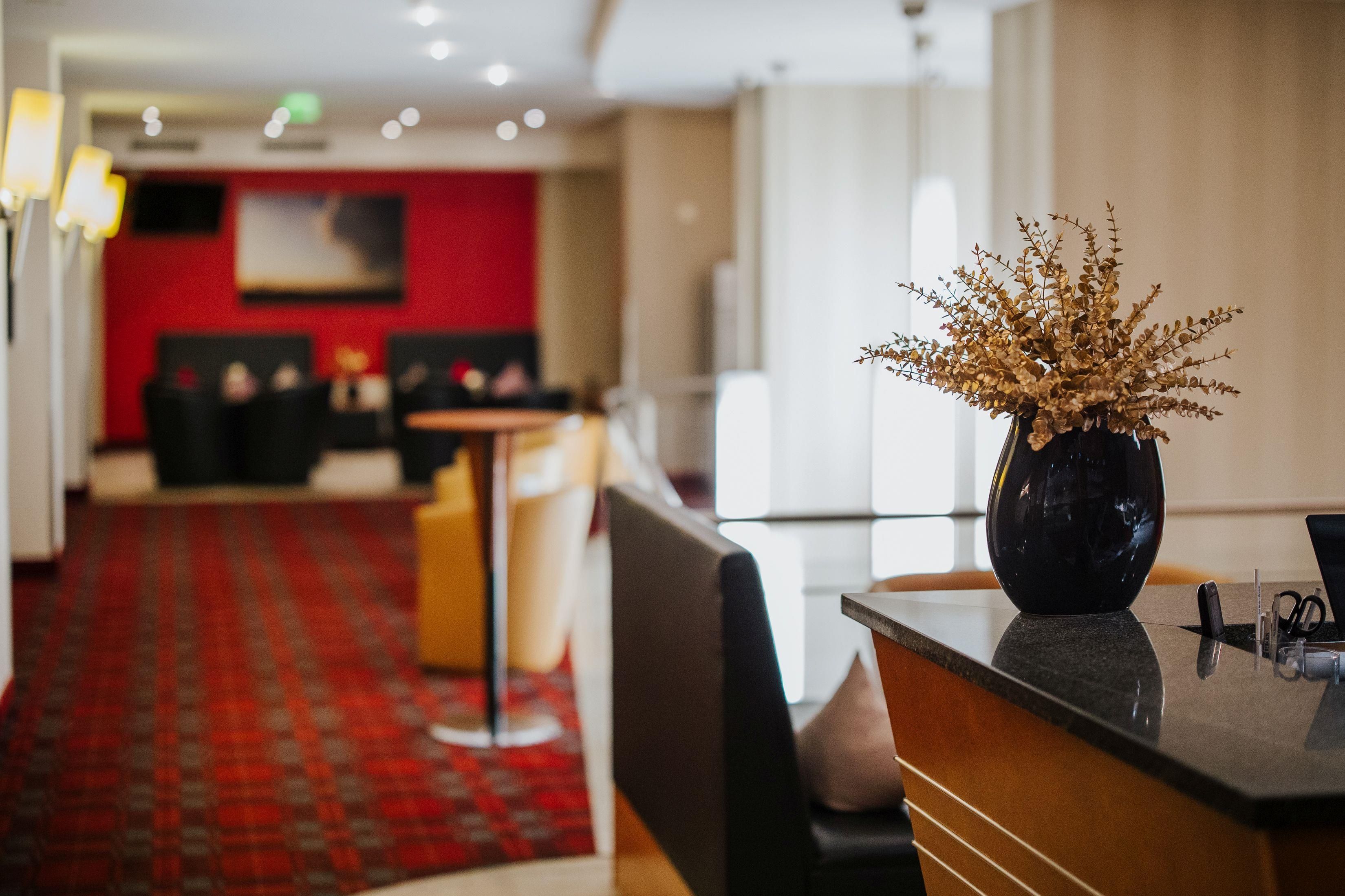 Un vestíbulo de hotel con mostrador de recepción, zona de estar y piso alfombrado en rojo.