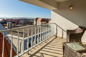 A balcony with a view of buildings, a railing, and a wicker chair. - Best Western Plus Hotel Bautzen (Bautzen)