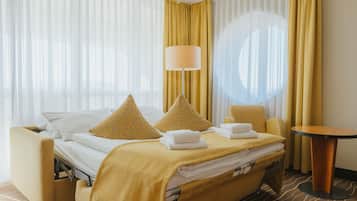 Ein Hotelzimmer mit einem Bett, zwei Sesseln, einem Tisch und einer Lampe.