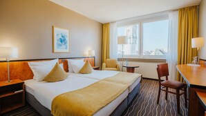 A hotel room with a large bed, two bedside tables, a chair, a small table, and a window with curtains. - Best Western Plus Hotel Bautzen (Bautzen)