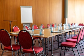 A conference room with a long table, red chairs, water bottles, and a whiteboard. - Best Western Plus Hotel Bautzen (Bautzen)