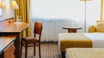 Habitación de hotel con cama, escritorio, silla, mesita y lámpara.