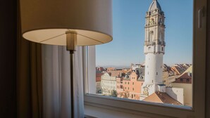 Una habitación con vistas a una torre histórica y edificios circundantes.