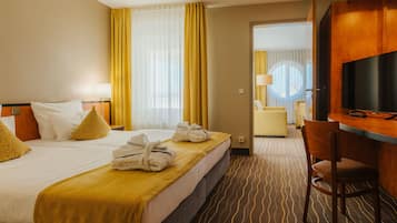 Una habitación de hotel con cama, escritorio, silla y televisor.