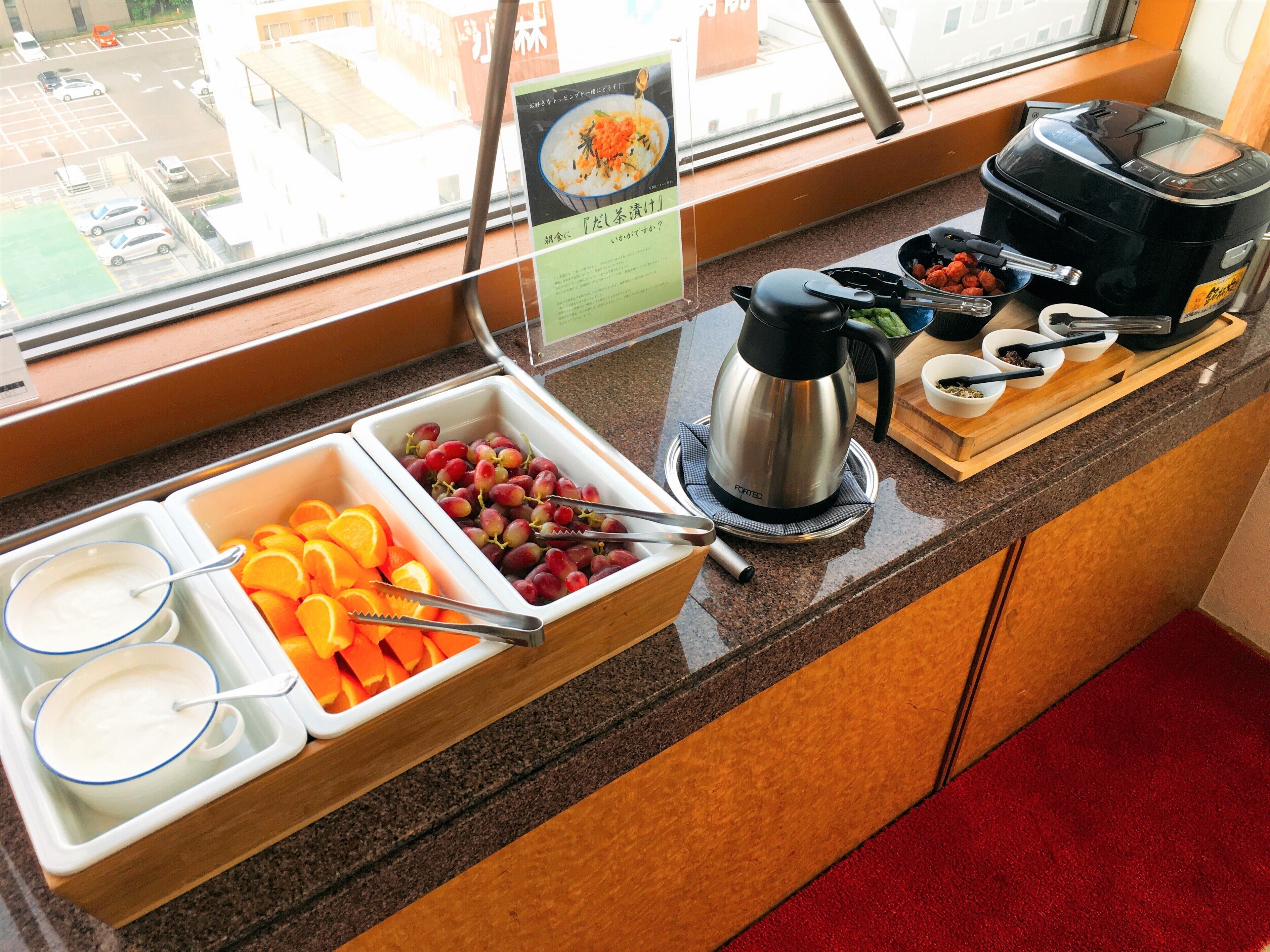 A breakfast buffet with fruits, yogurt, and coffee.