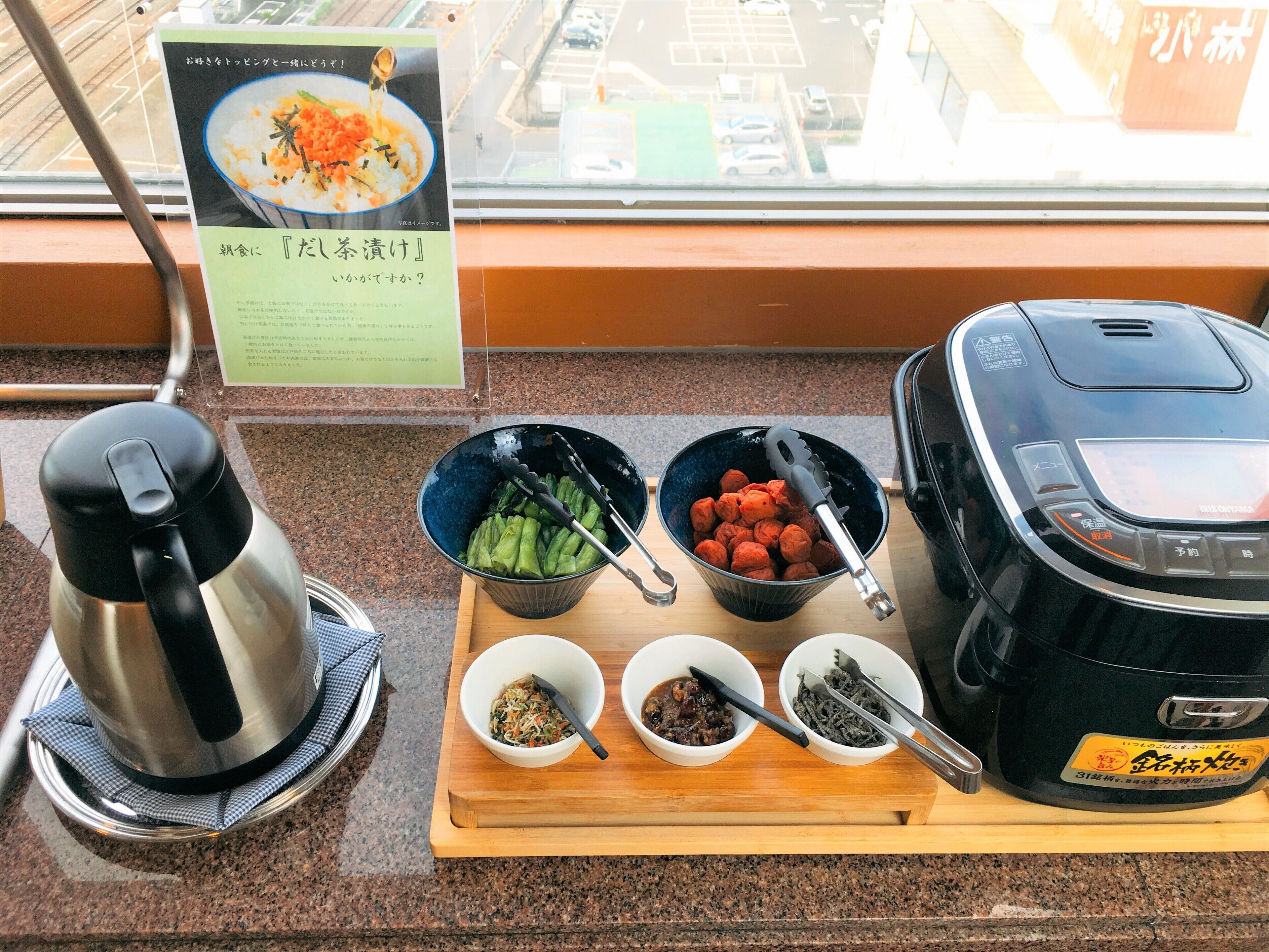 A kitchen counter with a kettle, bowls of food, and a rice cooker.