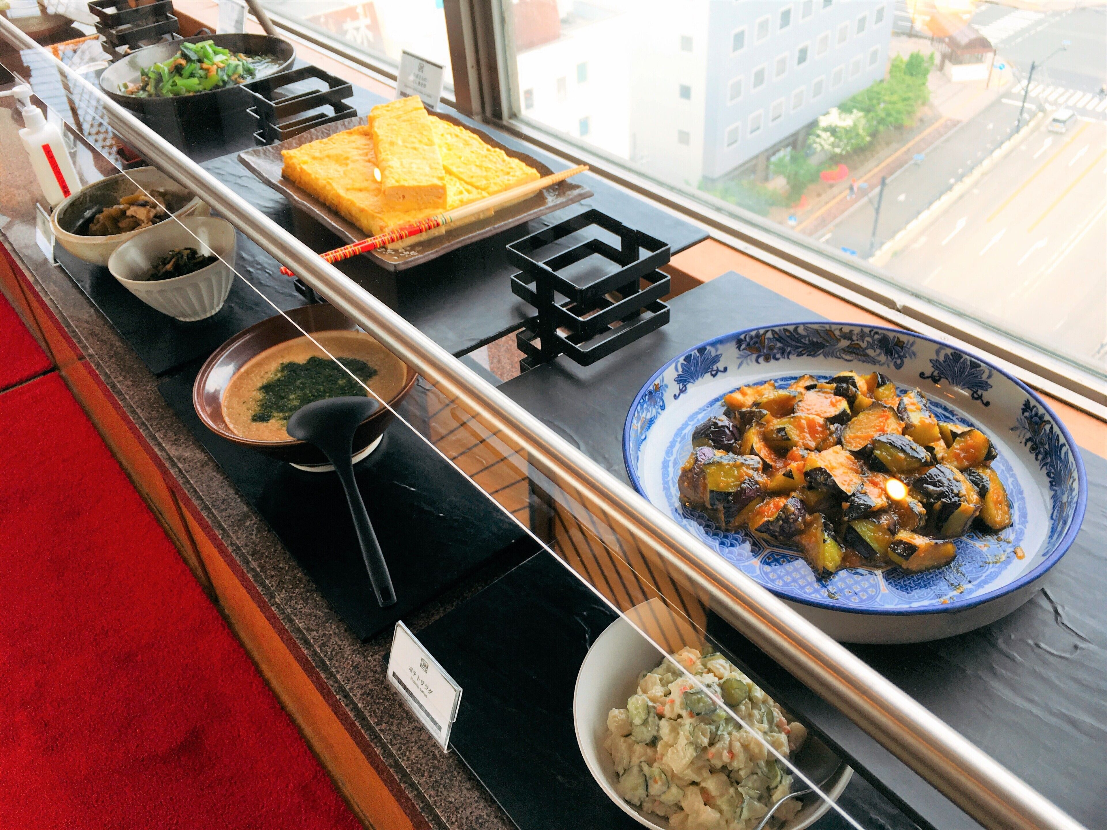 Een buffet met diverse gerechten, waaronder een grote kom groentestamppot, een schaal met groene groenten, en verschillende kleinere schaaltjes met andere etenswaren.
