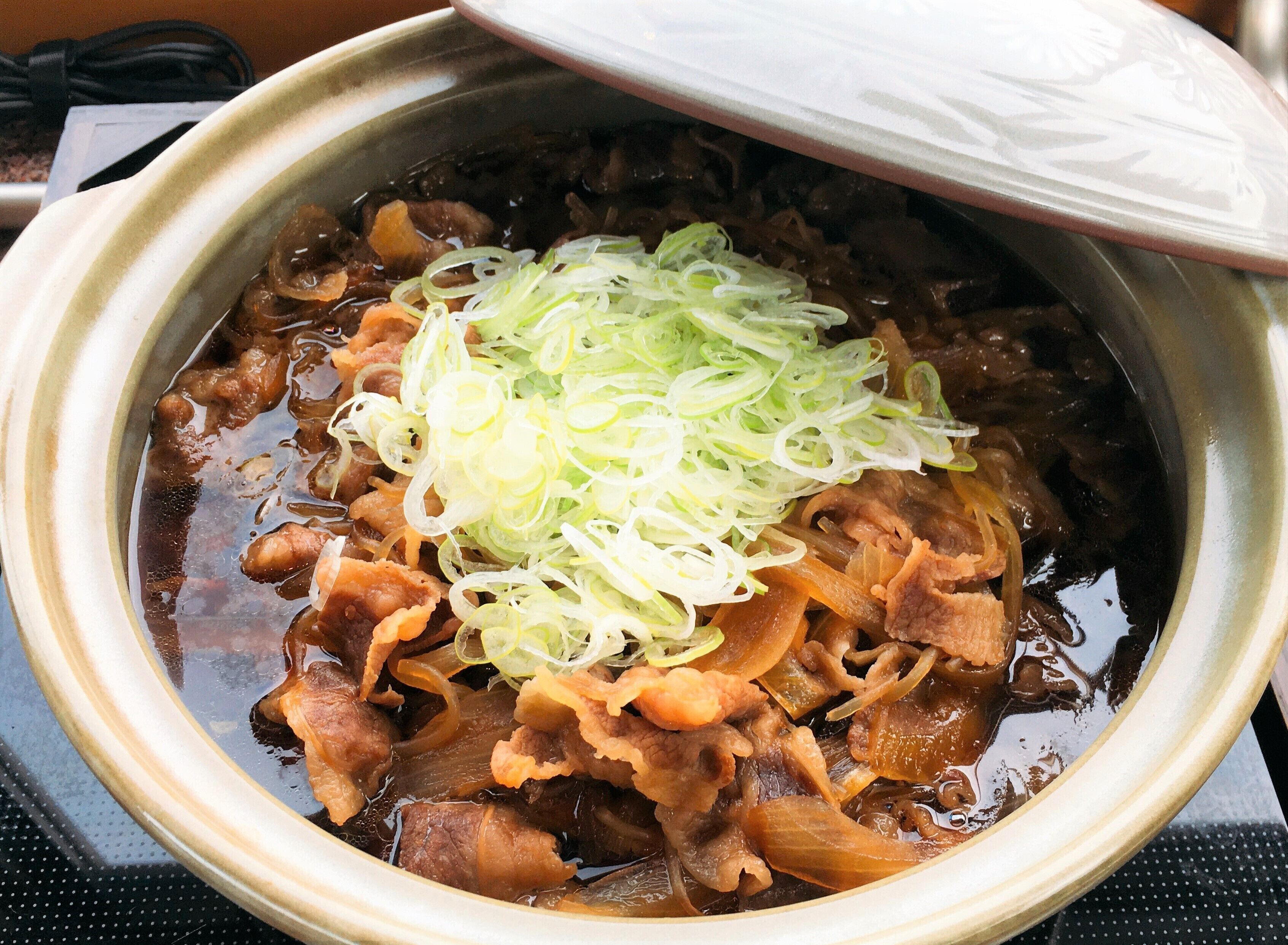 A bowl of soup with meat and shredded vegetables.