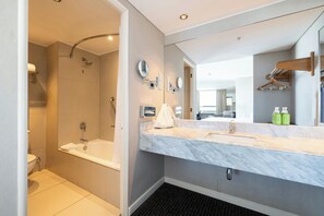Une salle de bain moderne avec une douche à l’italienne, un grand miroir et un comptoir en marbre.