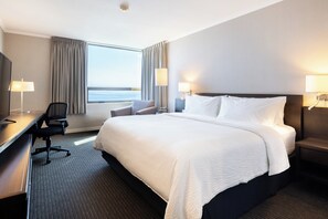 A hotel room with a large bed, a desk, a chair, and a view of the sea. - Holiday Inn Express Antofagasta by IHG (Antofagasta)