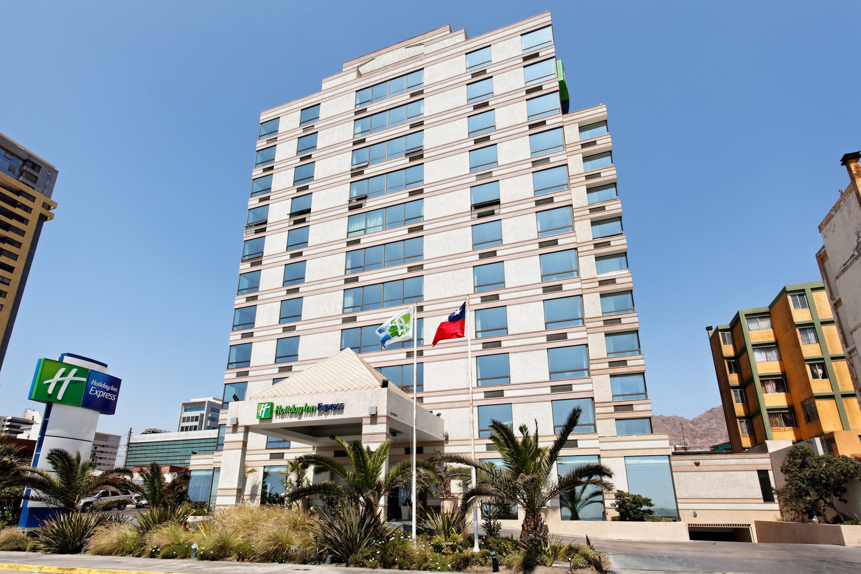 A multi-story hotel with a flat roof, large windows, and a flagpole with two flags.