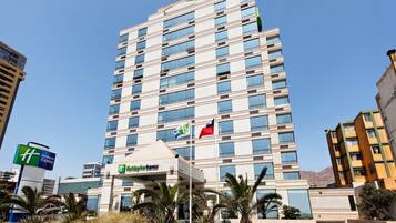 A multi-story hotel with a flat roof, large windows, and a flagpole with two flags.