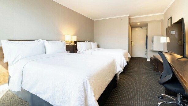 A hotel room with a large bed, a desk with a chair, a television, and a door leading to another room. - Holiday Inn Express Antofagasta by IHG (Antofagasta)