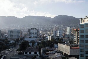 Un paysage urbain caractérisé par une diversité de hauteurs de bâtiments, comprenant à la fois des immeubles de faible et de grande hauteur, le tout se détachant sur un arrière-plan montagneux.