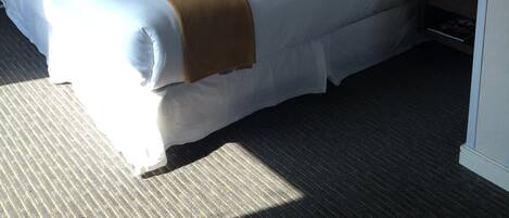 Habitación de hotel con una cama grande, lámparas de noche, un teléfono y un espejo.