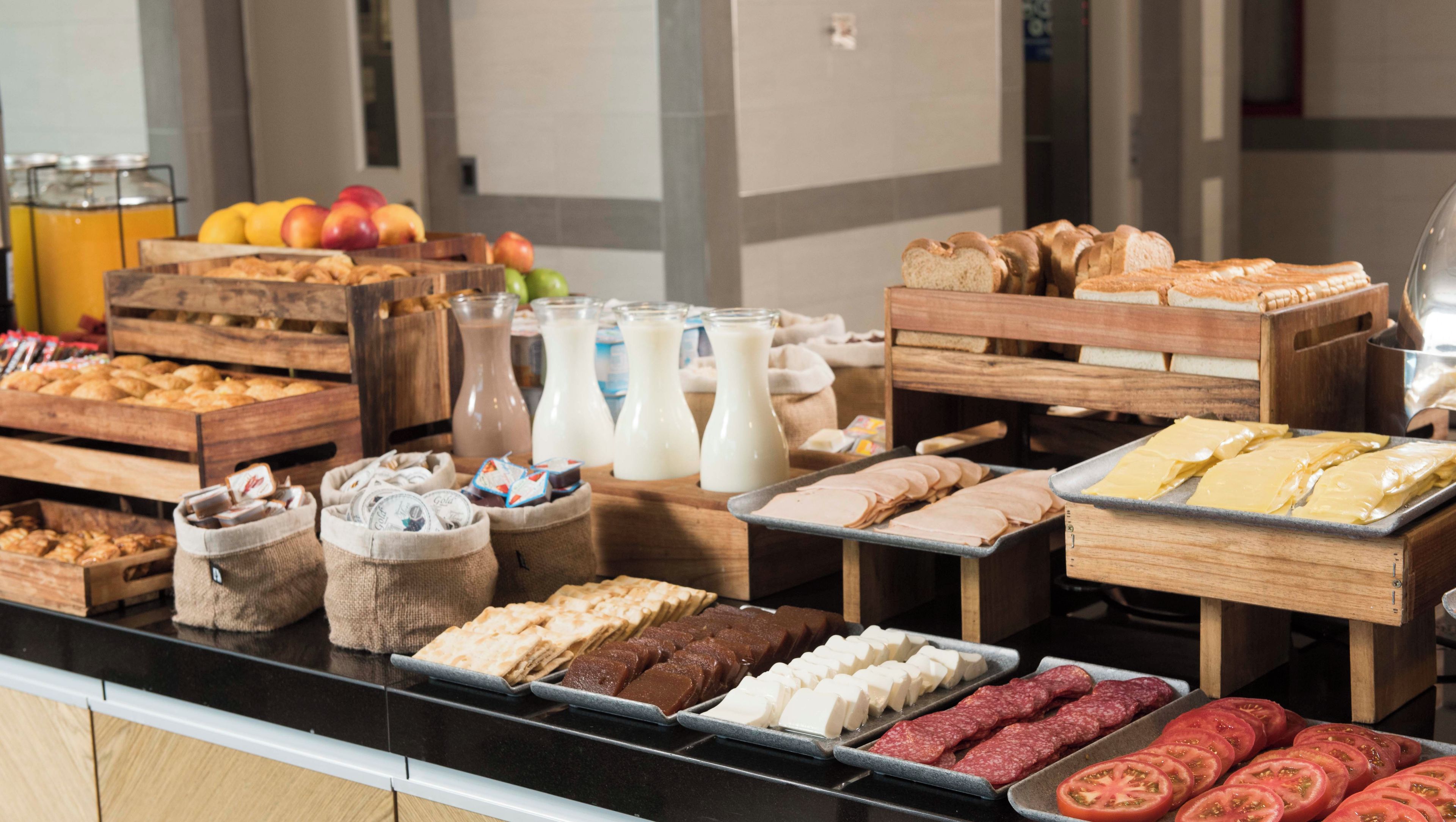Un bufé con diversas opciones de comida, incluyendo carnes, quesos y pastelería.