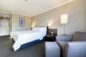 Une chambre d’hôtel avec un lit, une table de chevet, une chaise et une lampe.