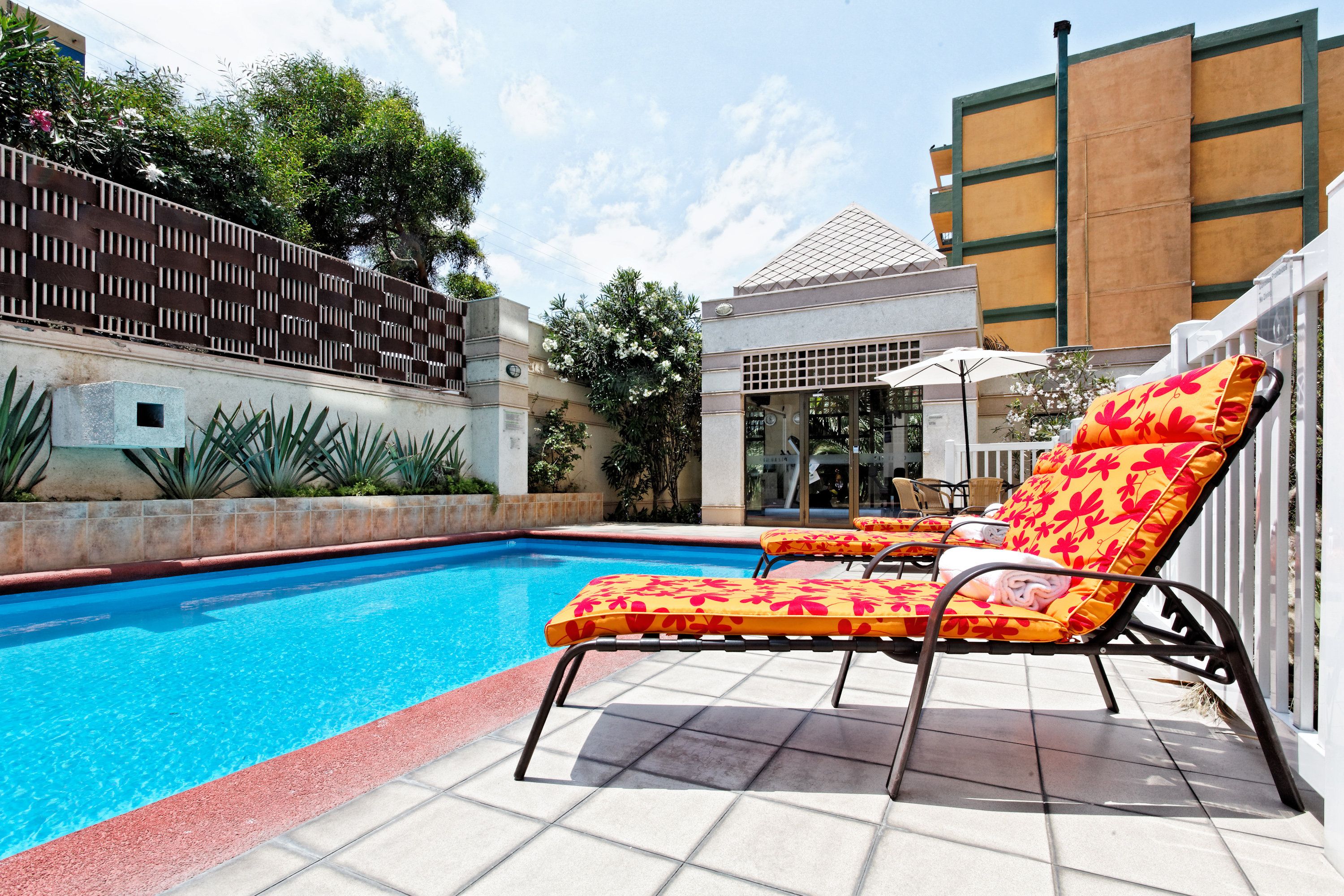 A swimming pool with lounge chairs and a tiled deck.