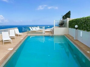 Relax by the ocean-view pool surrounded by lounge chairs and a modern seating area.