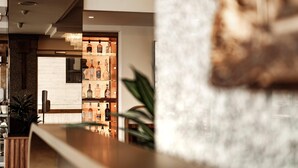 Una zona de bar con mostrador de madera y estanterías con botellas.