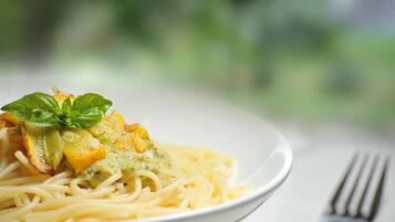 A plate of spaghetti with a green sauce and a basil leaf garnish.