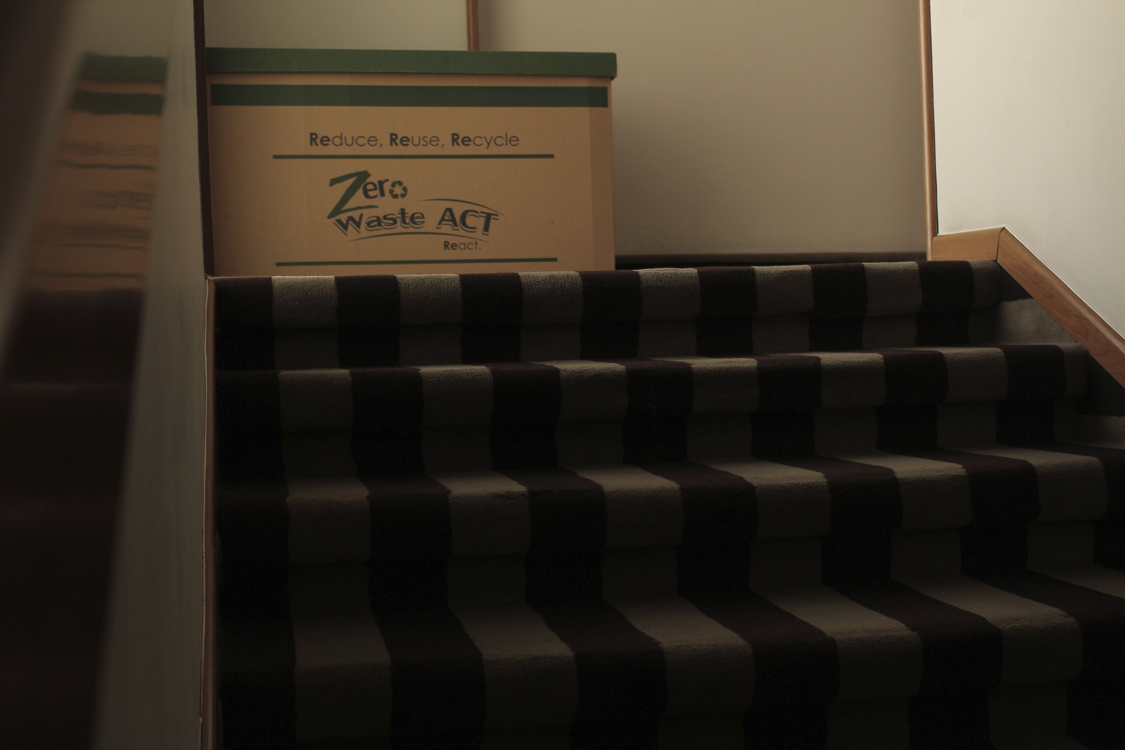 A staircase with a trash bin labeled "Zero Waste ACT" at the top.