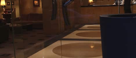 A lobby with a reception desk, glass walls, and a large potted plant.