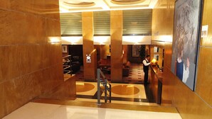 A lobby with a reception desk, a staircase, and a seating area. - Plaza Hotel (Beirut)