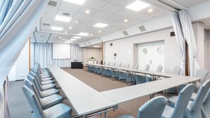 A conference room with a long table, rows of chairs, and a carpeted floor. - Qubus Hotel Zielona Gora (Zielona Gora)