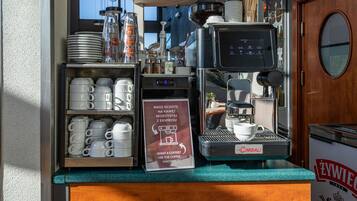 Een koffieapparaat met een bordje in een vreemde taal, bekers en borden op een aanrecht.