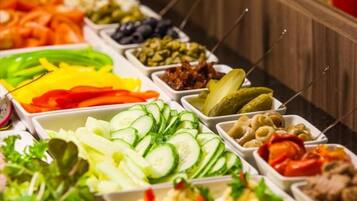 A buffet with various food options including vegetables, fruits, and meats.