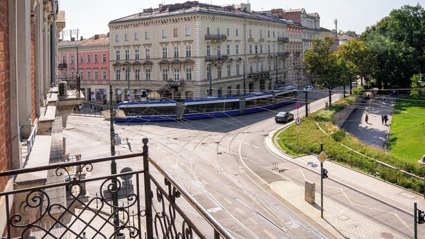 A tram on a curved track with buildings in the background. - Polonia Hotel (Kraków)