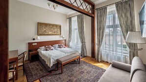A bedroom with a bed, bench, desk, chair, and a large window with curtains. - Polonia Hotel (Kraków)