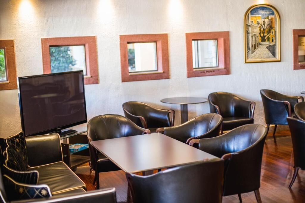 Ein Hotelzimmer mit Ledersesseln, einem Fernseher und gerahmten Kunstwerken an der Wand.