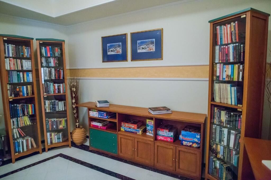 Una biblioteca con estanterías, un escritorio de madera y dos cuadros en la pared.