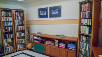 Una biblioteca con estanterías, un escritorio de madera y dos cuadros en la pared.