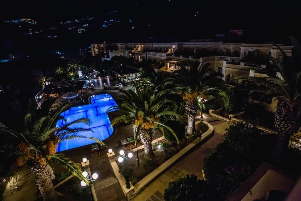 Een resort met een groot zwembad, palmbomen en een goed verlicht buitengebied.