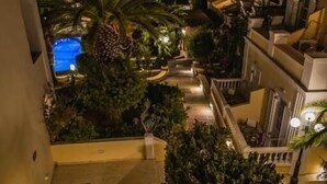 Vista nocturna de un edificio de varios pisos con una escalera que lleva a una terraza.