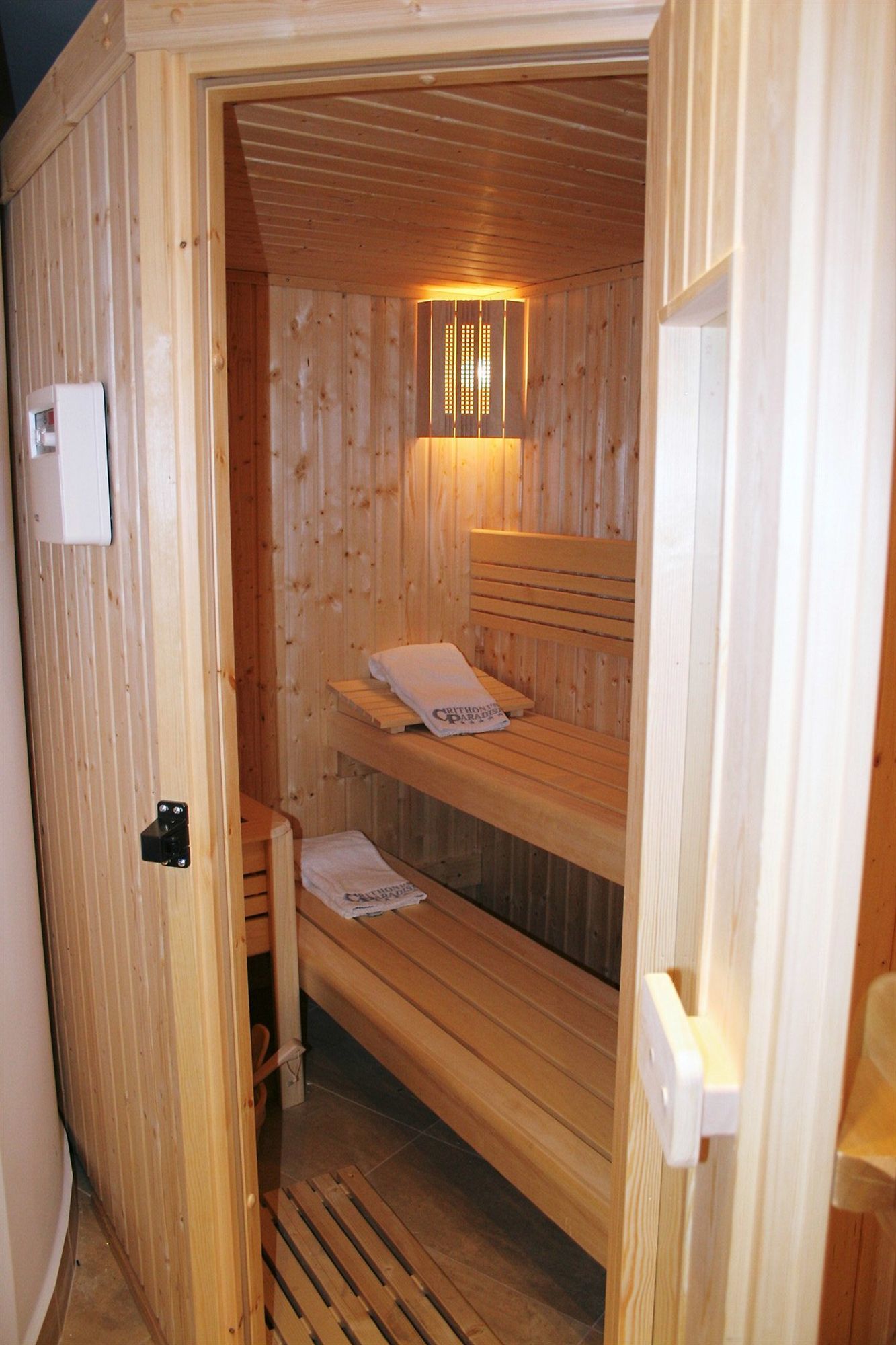 A wooden sauna with two benches and a wall-mounted light fixture.