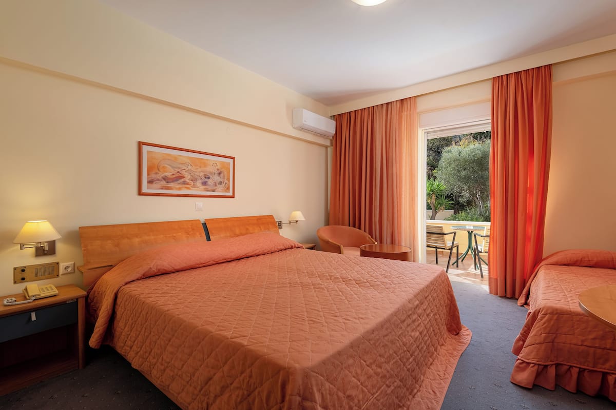 A hotel room with a large bed, a bedside table with a lamp, a chair, and a small table.