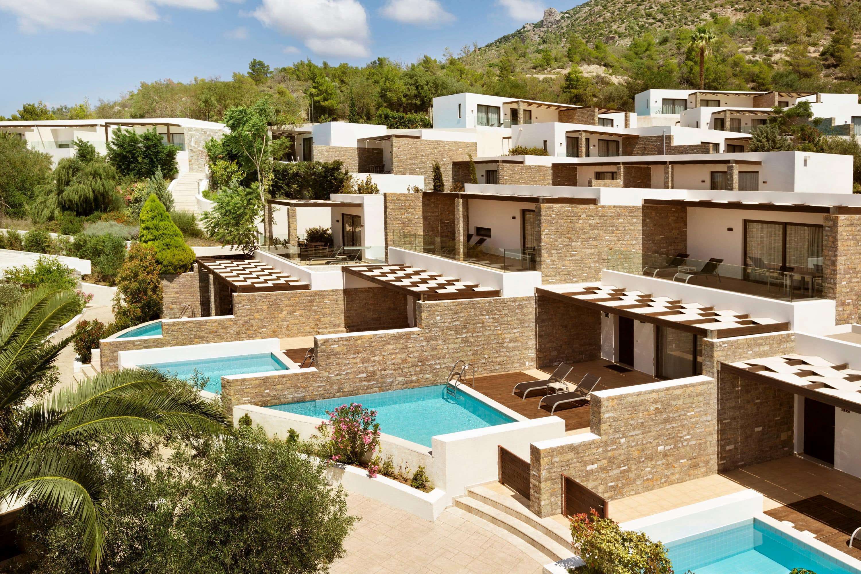 Un resort moderno con varias piscinas, zonas de estar al aire libre y un telón de fondo montañoso.