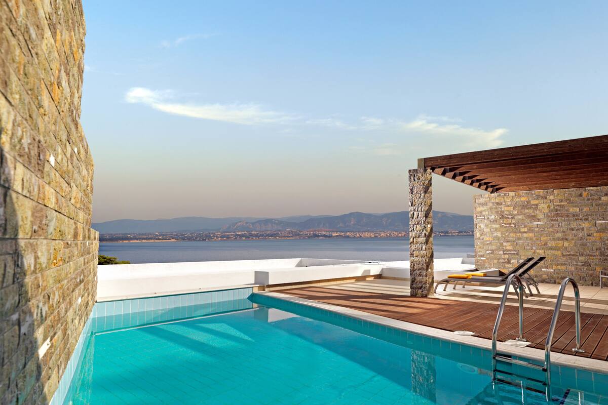 A pool with a view of the sea and mountains.