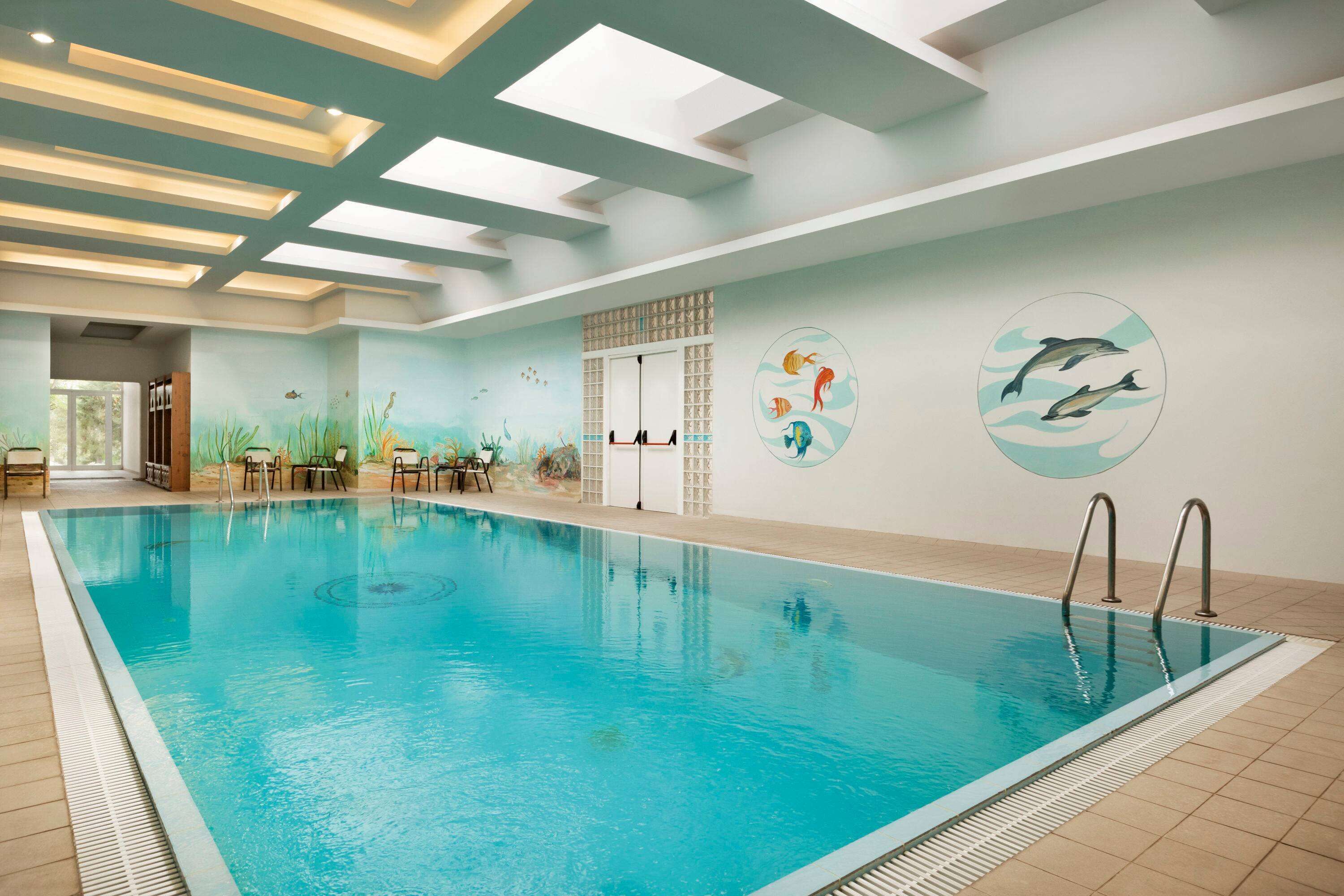 Una piscina interior con agua cristalina, suelo de baldosas y techo con tragaluces.