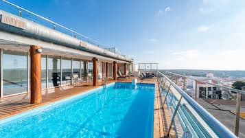 Relax by the pool surrounded by lounge chairs and sunbeds, with a city view.