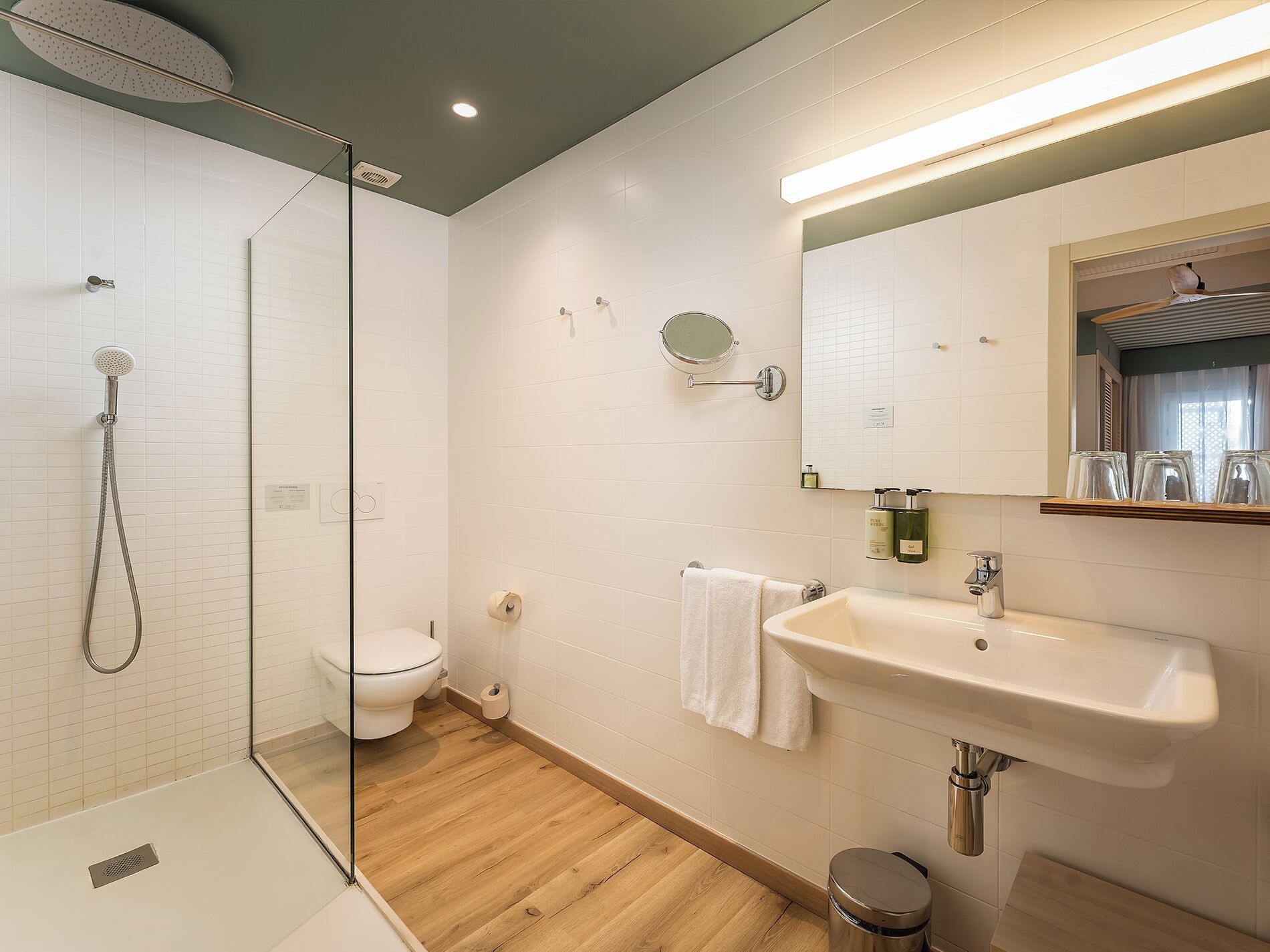 Une salle de bain moderne avec une douche à parois de verre, des toilettes, un lavabo avec un miroir et un porte-serviettes.