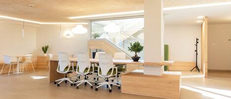 A modern office space with a reception desk, meeting tables, and chairs.