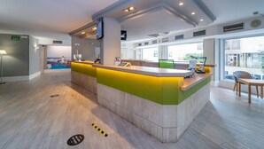 Un espace d’accueil moderne doté d’un comptoir, de sièges et de grandes fenêtres.