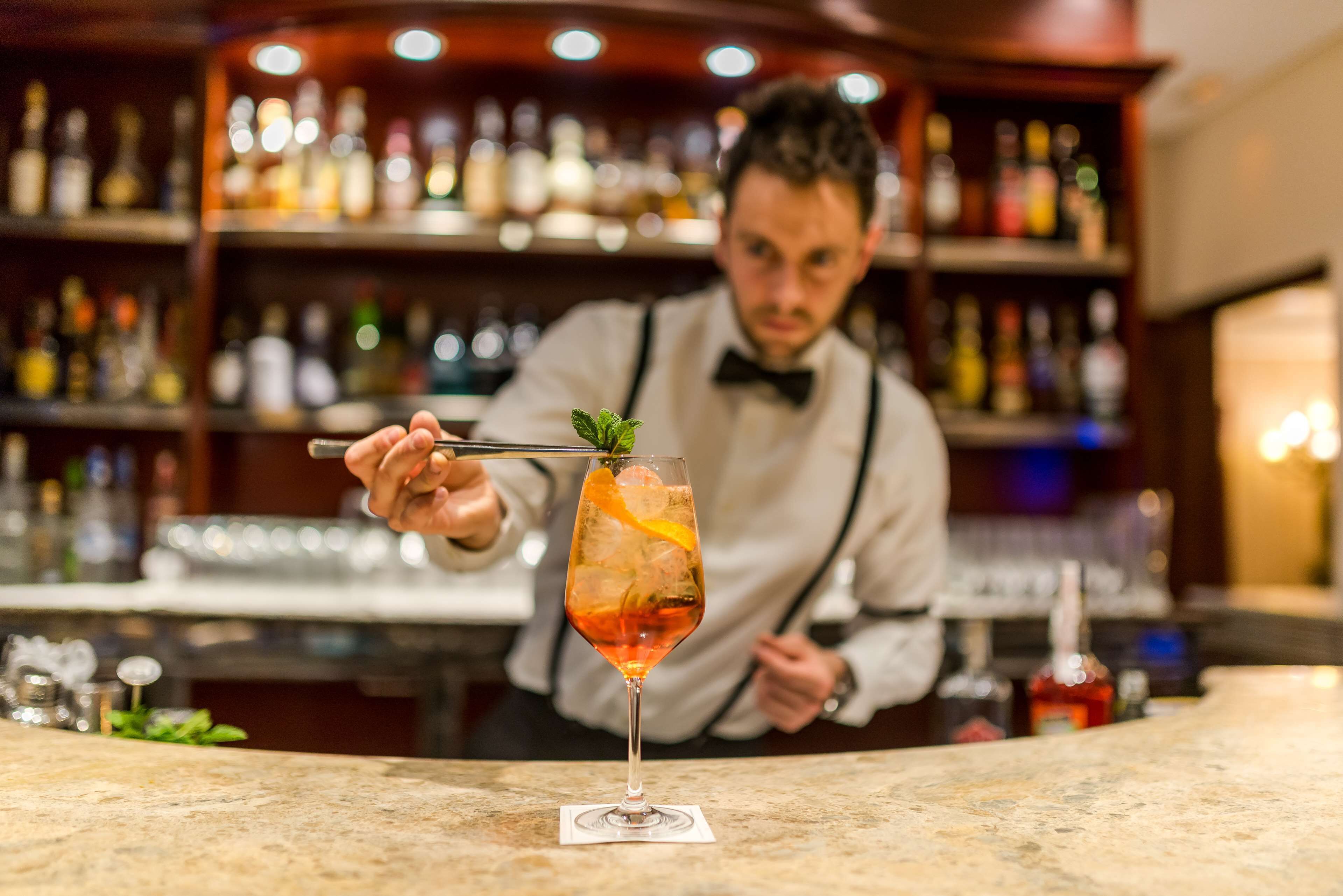 A bartender preparing a cocktail with a mint garnish.